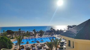 Un resort con una gran piscina, palmeras y vista al océano.