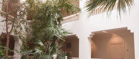 A spacious atrium with a high ceiling, marble flooring, and a central staircase.