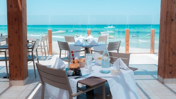 Mesa lista para comer con vista al océano y la playa.