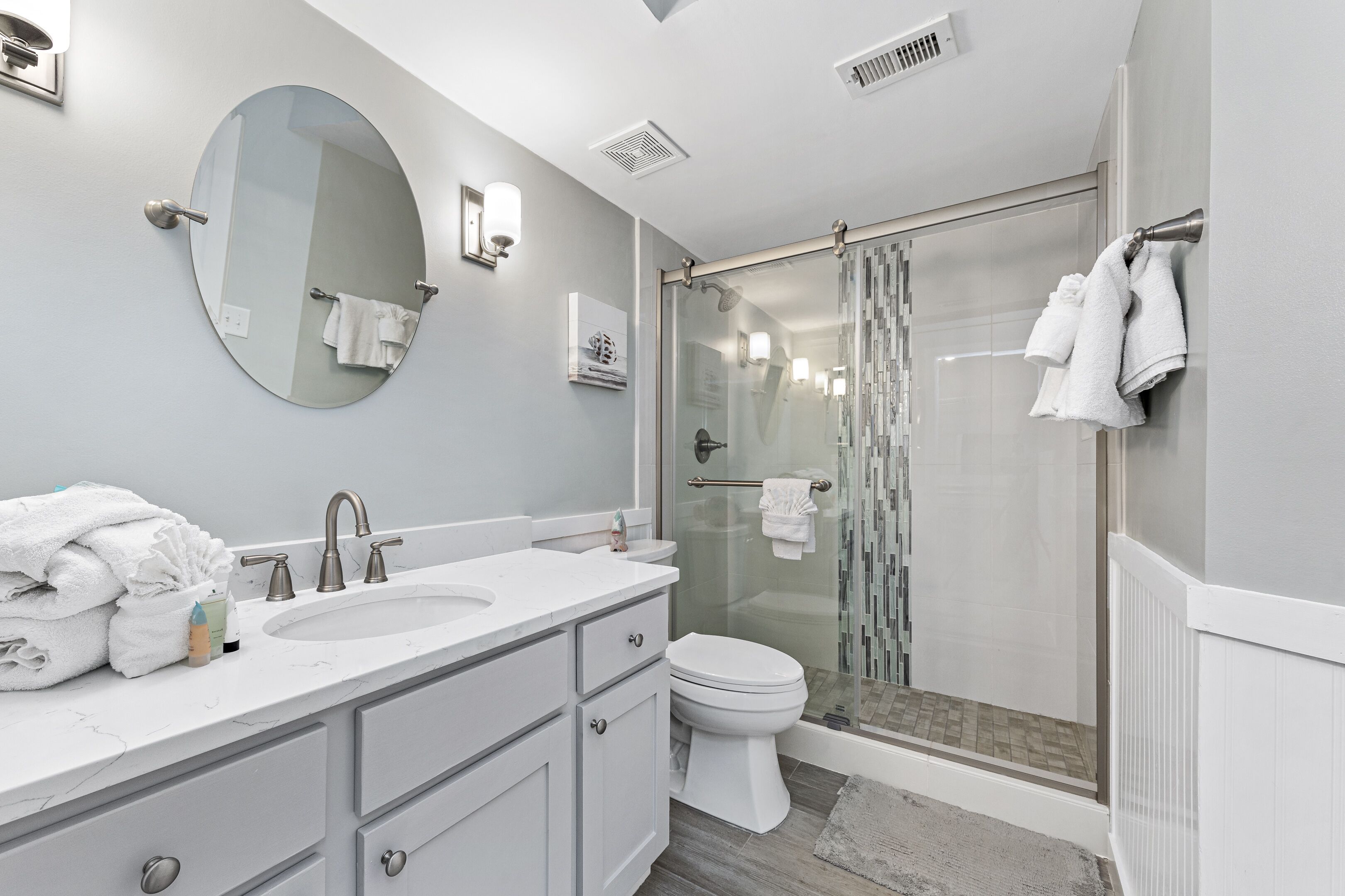 A modern bathroom with a double sink vanity, a toilet, and a glass-enclosed shower.