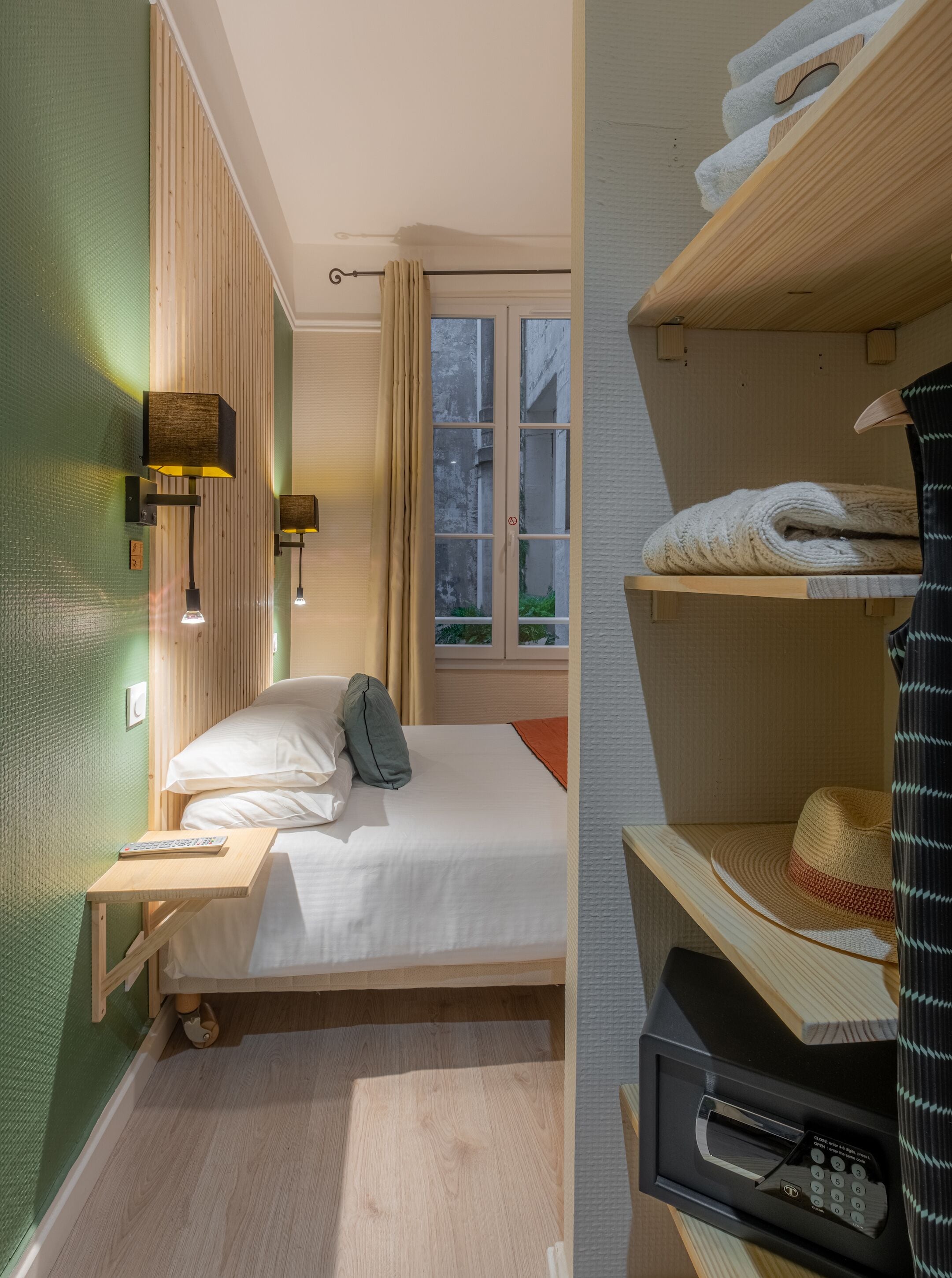 A neatly arranged bedroom with a bed, bedside table, and a window with curtains.