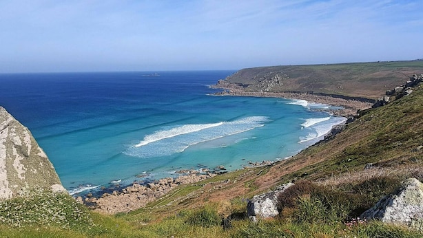 Un paisaje costero con vista despejada al océano, acantilados rocosos y terreno cubierto de hierba.