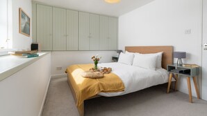 Un dormitorio con cama, mesita de noche, lámpara y una lámpara colgante.