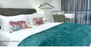 Una habitación de hotel con cama, escritorio y ventana con cortinas.