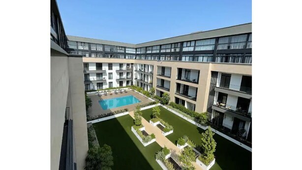 Un edificio moderno con un patio central, piscina y varios balcones.