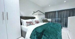 Un dormitorio moderno con cama, escritorio y armario.