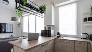 Una cucina moderna con isola integrata, un divano grigio e una TV a parete.