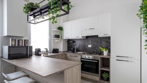 Una cucina moderna con isola centrale, mobili bianchi e forno integrato.