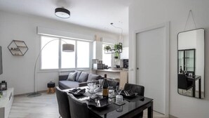 Un soggiorno moderno con zona pranzo, divano, tavolino e un grande specchio.