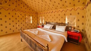A room with a large bed, two bedside tables, and a patterned wallpaper.