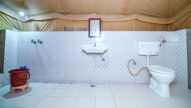 A bathroom with a sink, toilet, and bucket.