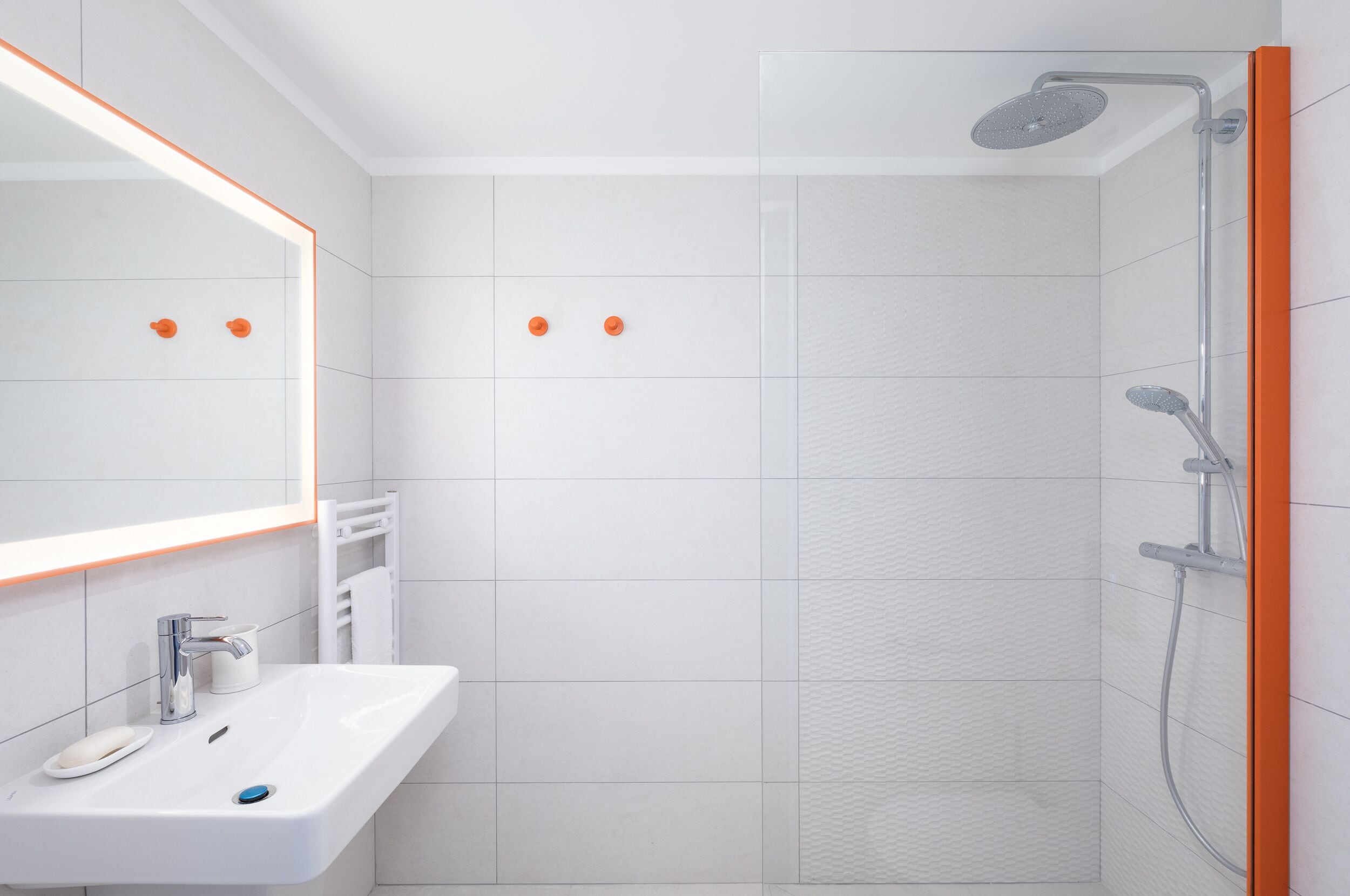 A modern bathroom with a white sink, mirror, and shower.