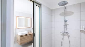 A modern bathroom with a glass door, a white sink, a wooden vanity, and a shower with a handheld showerhead.