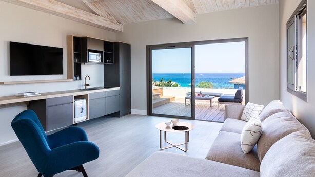Een moderne woonkamer met een flatscreen televisie, een blauwe fauteuil, een beige bank en een kleine tafel.