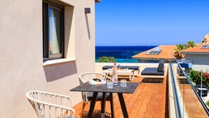 A balcony with a wooden table, chairs, and a bottle of water.
