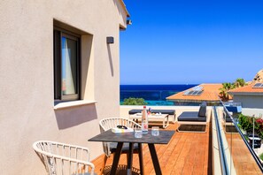 A balcony with a wooden table, chairs, and a bottle of water.