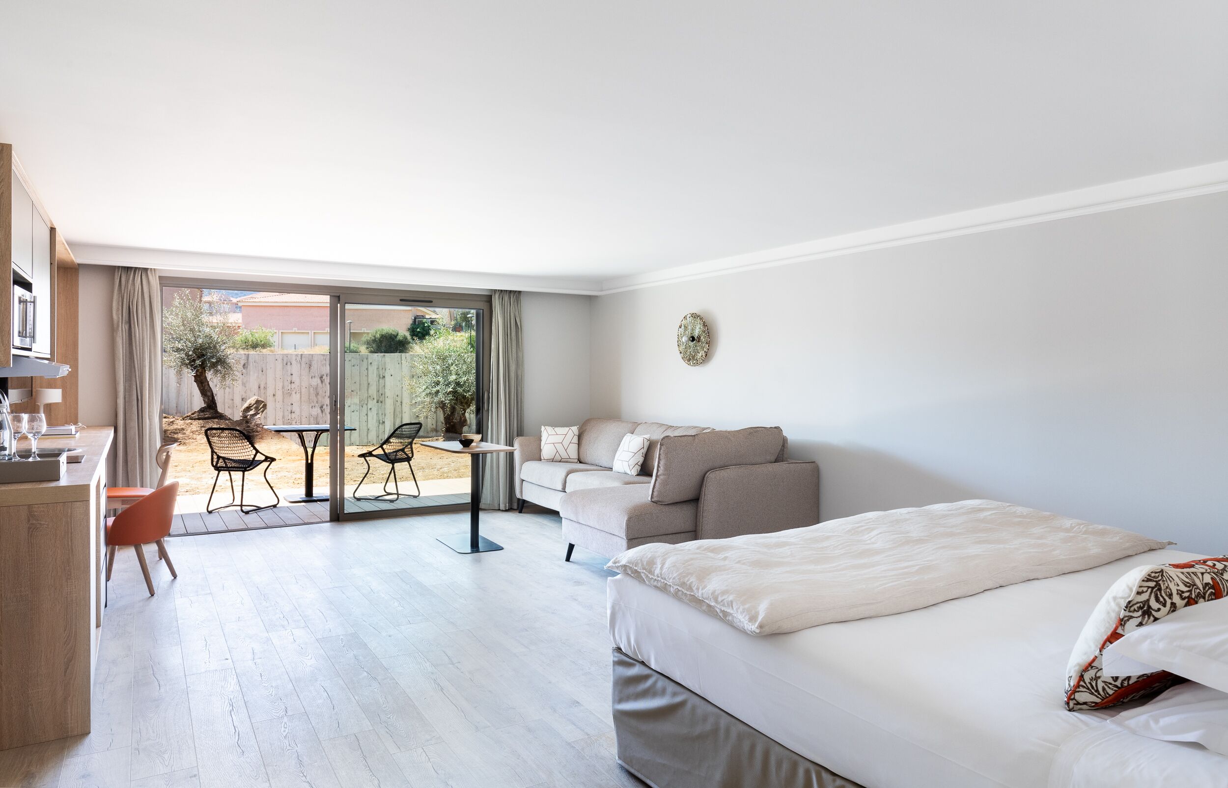 Una habitación de hotel moderna con una cama grande, un sofá, una mesa de comedor y una zona de cocina.