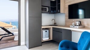 Een moderne keuken met een ingebouwde magnetron, oven en koffiezetapparaat, een grote flatscreen-tv en uitzicht op zee.