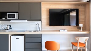 Een moderne keuken met een ingebouwde magnetron, een koelkast, een spoelbak en een flatscreen televisie aan de muur.