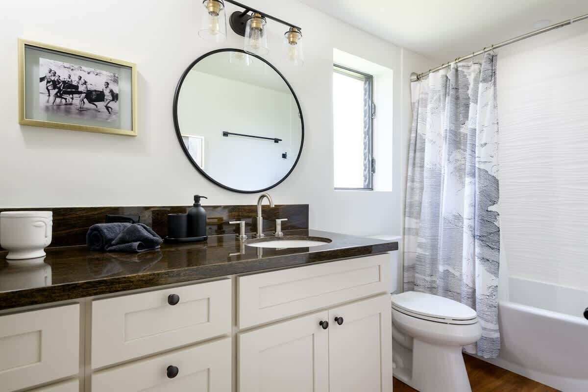 Un bagno con lavandino, specchio, WC e vasca da bagno.