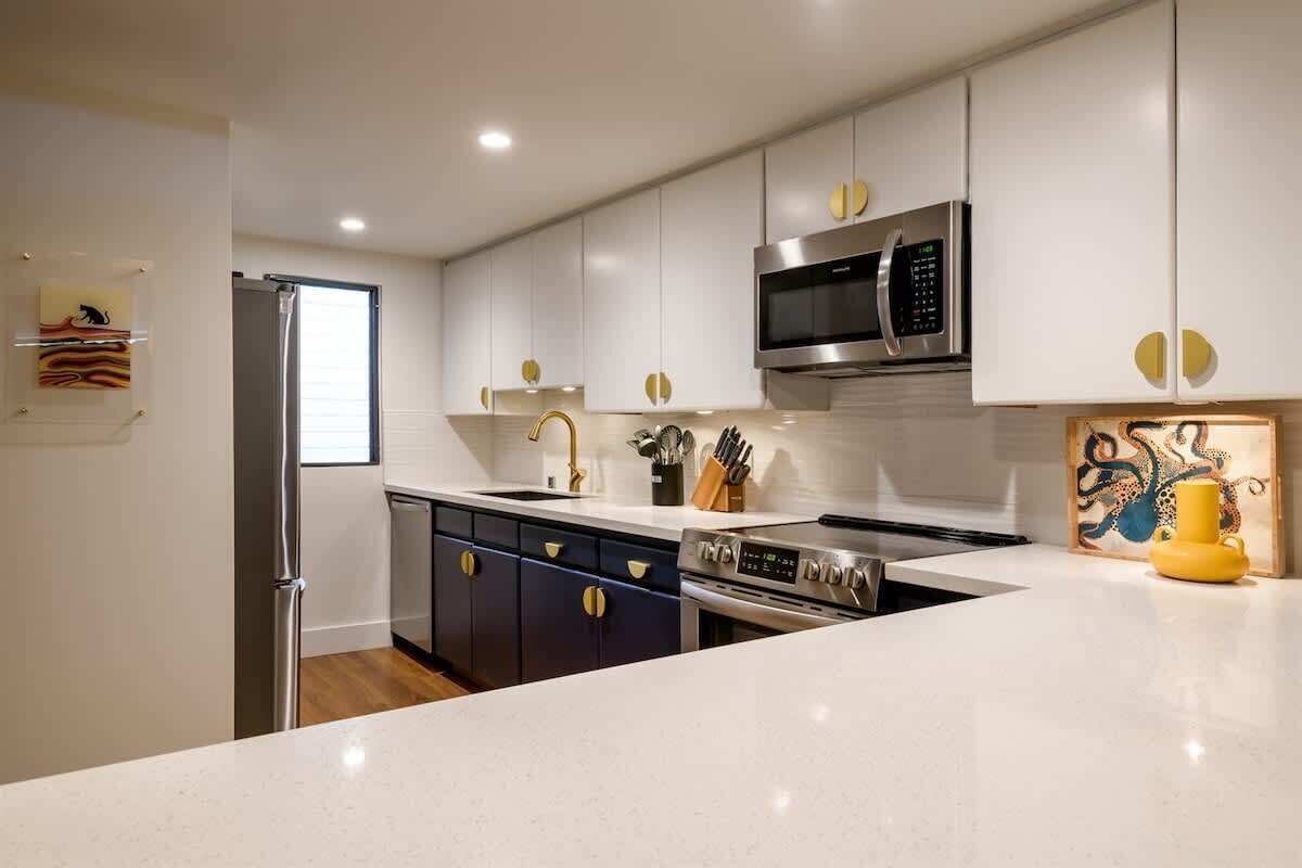A modern kitchen with stainless steel appliances, white cabinetry, and a central island.