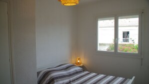 Een slaapkamer met een bed, een raam en een lamp.