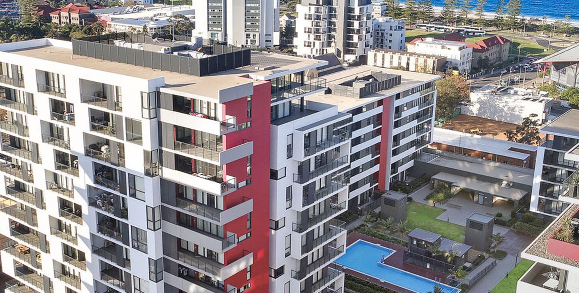 A high-rise residential building with multiple balconies, a rooftop terrace, and a swimming pool.