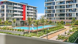 A modern apartment building with a swimming pool and landscaped gardens. - Wollongong CBD Ocean View Apartment (Wollongong)