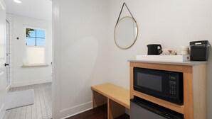 A compact kitchen with a microwave, oven, and a small bench. A wooden shelf holds a kettle and cups. - Summit Lofts, Mt Shasta, 2 Queen Beds #209 (Mt Shasta)