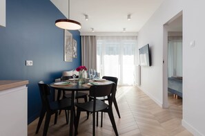 A modern dining area with a round table, chairs, and a vase of flowers. - Stylish Apartment with Balcony | Parking | 500 m to the Beach (Kołobrzeg)
