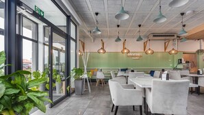 A modern restaurant interior with glass doors, green walls, white chairs, and pendant lighting. - Air-conditioned Apartment | Swimming Pool in the Property, Close to the Sea (Sarbinowo)