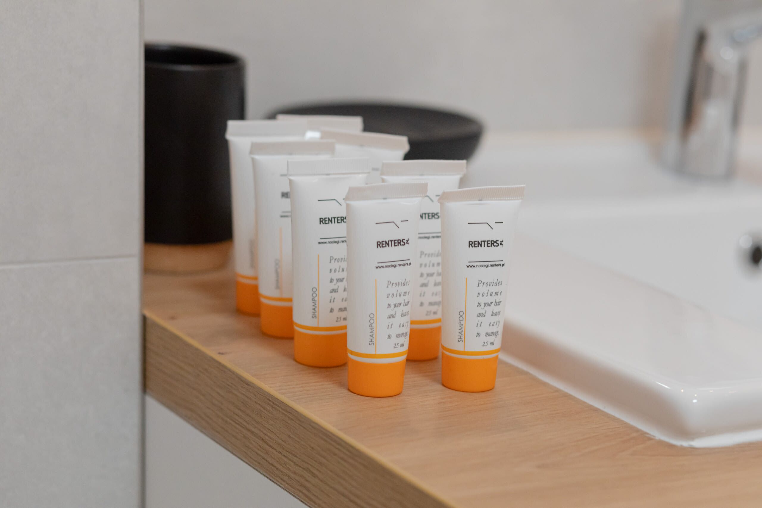 A row of toiletries on a wooden shelf in a bathroom.