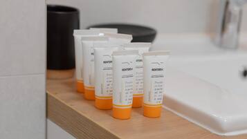 A row of toiletries on a wooden shelf in a bathroom.