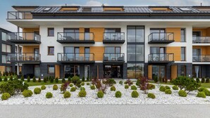 A modern multi-story residential building with balconies, large windows, and a landscaped garden area. - Air-conditioned Apartment | Swimming Pool in the Property, Close to the Sea (Sarbinowo)