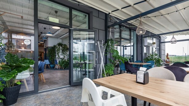 An office space with glass walls, indoor plants, and modern furniture. - Air-conditioned Apartment | Swimming Pool in the Property, Close to the Sea (Sarbinowo)