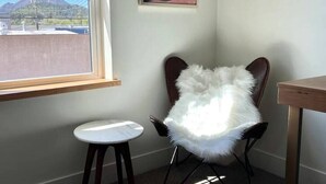 A corner room with a white fluffy chair, a small round table, and a window with a view of a mountain. - Summit Lofts, Mt Shasta, View of Lava Dome Volcano #208 (Mt Shasta)
