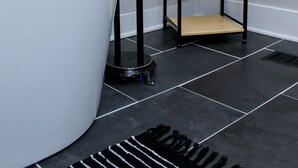 Ein modernes Badezimmer mit einer weißen Badewanne, einem schwarzen Duschkopf und einem schwarzen Metallregal.