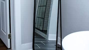Une salle de bain avec un lavabo blanc, un miroir et un carrelage gris foncé.
