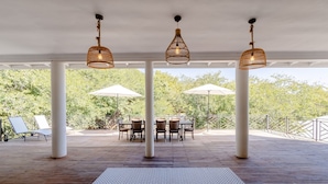 An outdoor patio with a wooden deck, a patterned rug, and a table with chairs. - Nkosi Guest Lodge (Victoria Falls)
