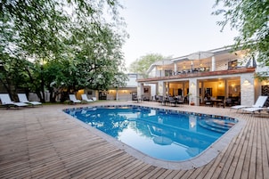 Un área de piscina con sillones de descanso y un comedor.