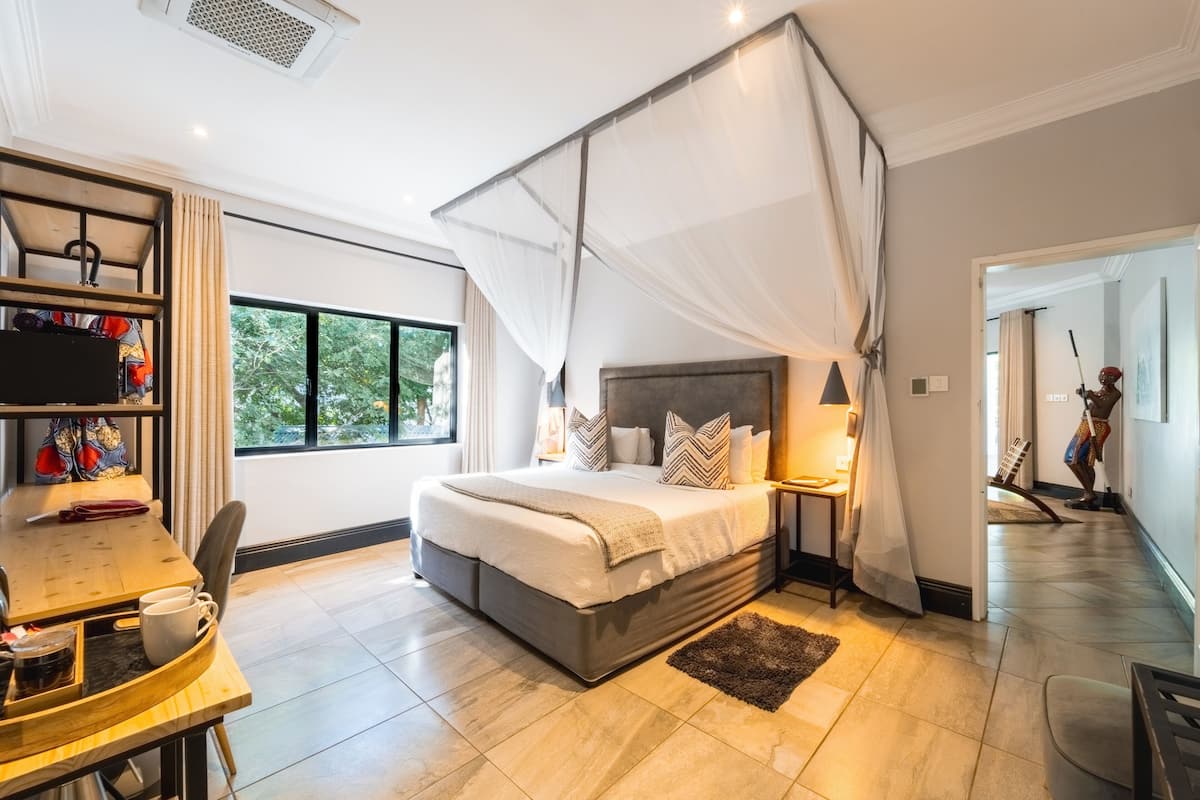 A bedroom with a large bed, bedside tables, a desk, and a chair.