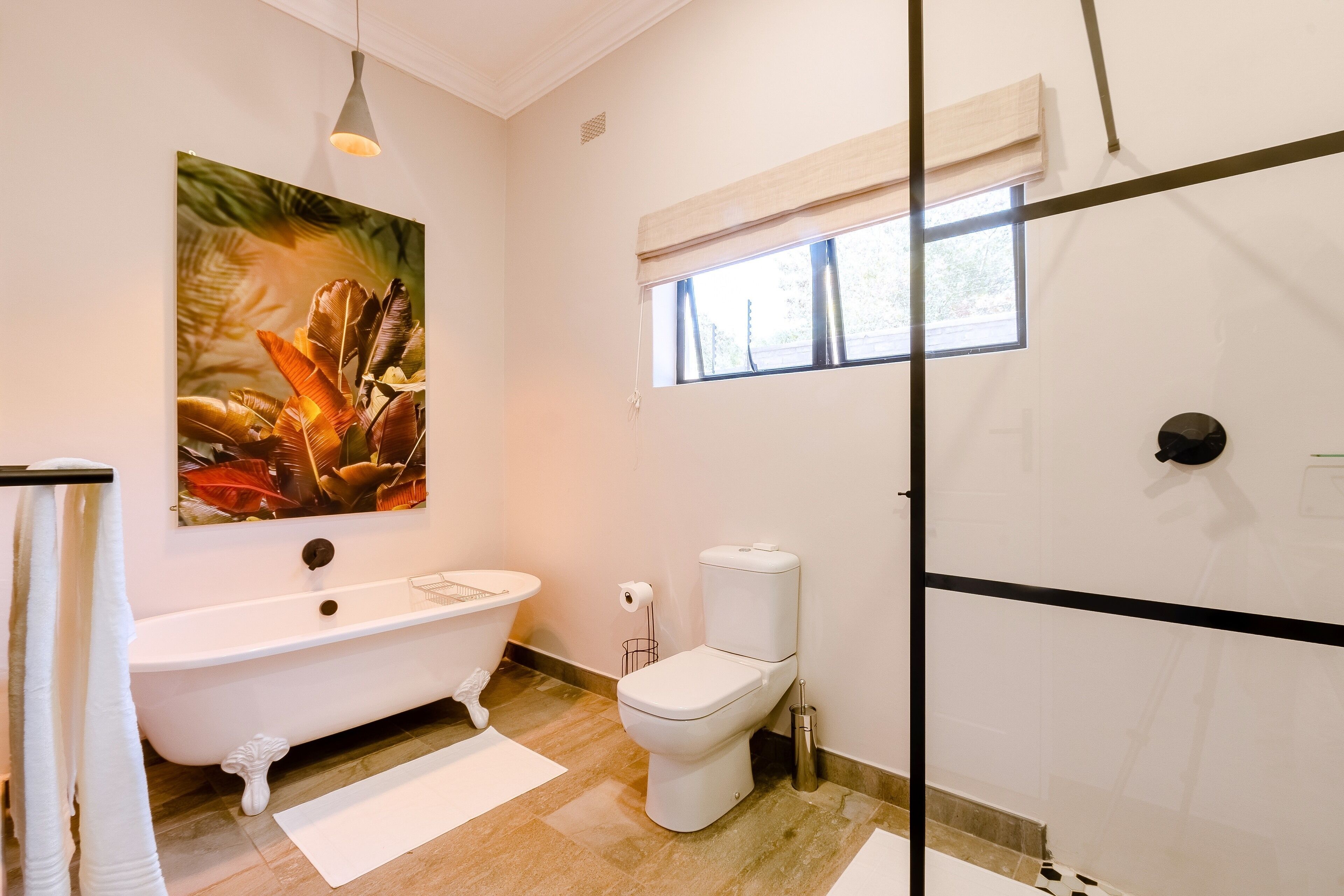 A bathroom with a freestanding bathtub, a toilet, and a large window.