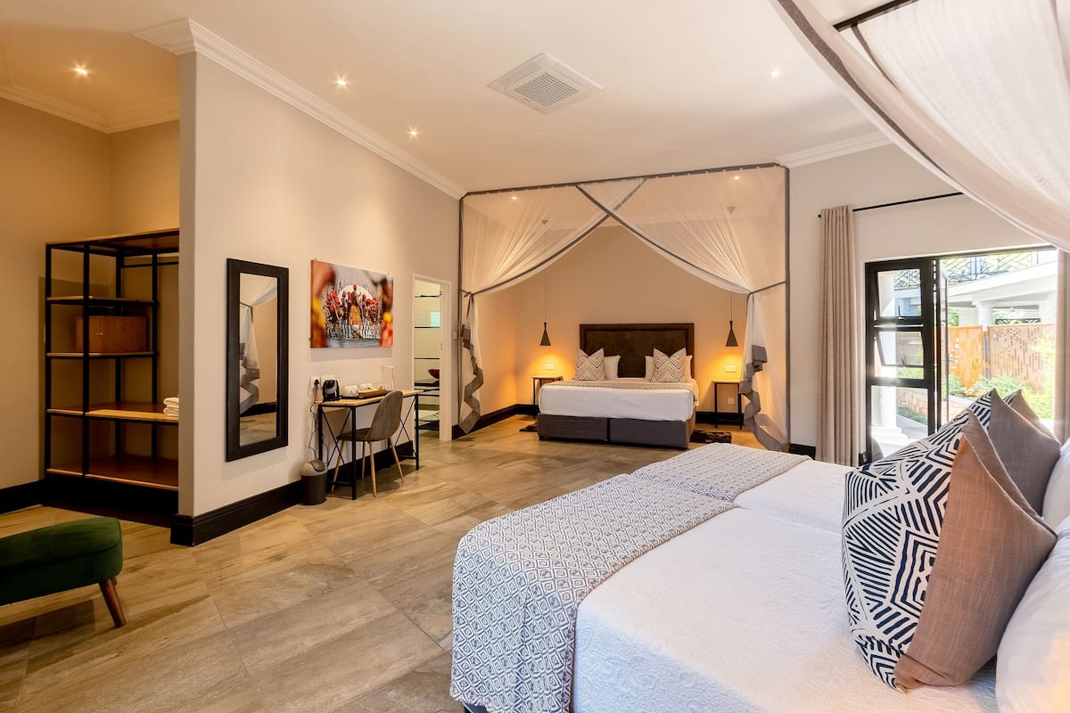 A hotel room with a large bed, a desk, and a chair. There is a window with curtains and a view of the outside.