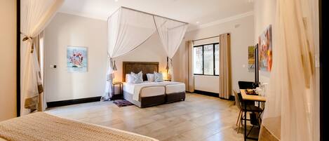 A spacious bedroom with a large bed, a bedside table, a desk, and a chair.