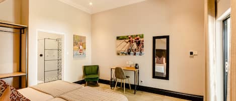 Quarto de hotel com cama, escrivaninha, cadeira e obras de arte nas paredes.