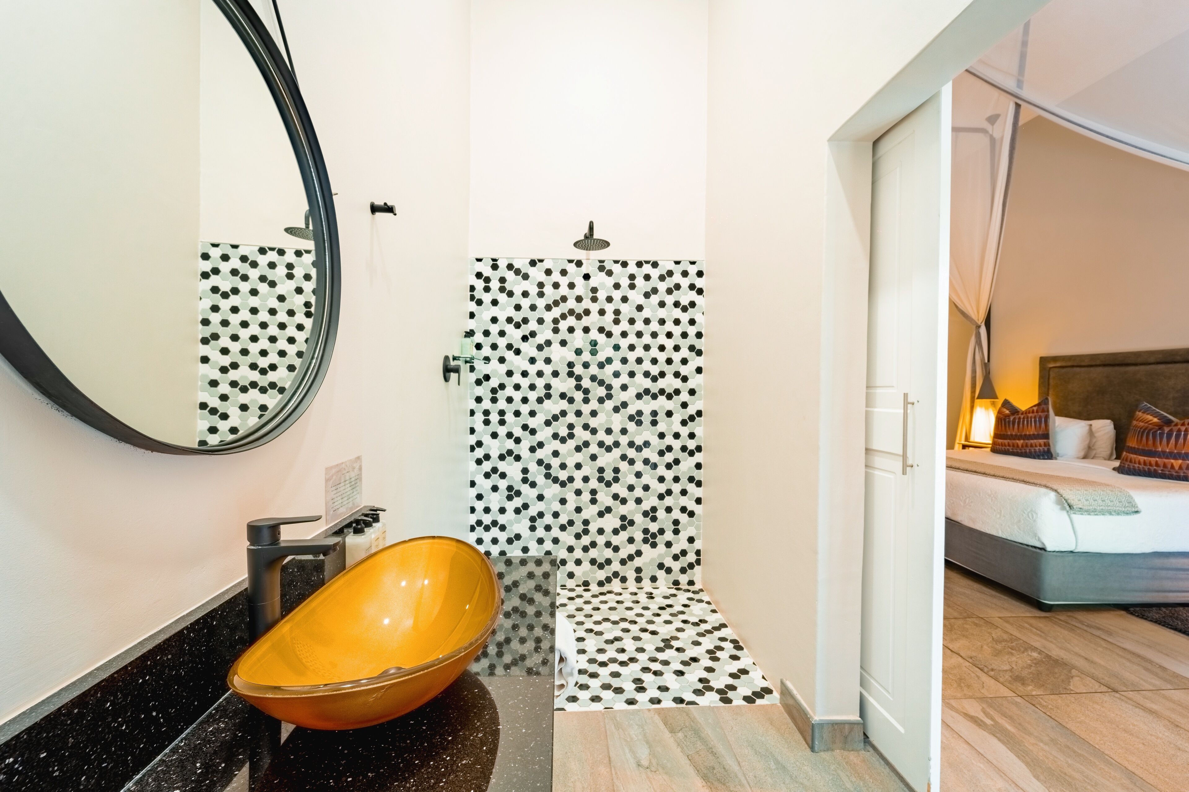 A bathroom with a black and white polka dot shower wall, a round yellow sink, and a mirror.
