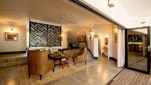 A spacious living area with a dining set, a large decorative wall, and a staircase leading to another level. - Nkosi Guest Lodge (Victoria Falls)