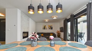 A modern dining area with a wooden table, teal placemats, and a vase of flowers.