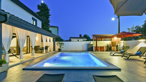 A swimming pool with lounge chairs and a covered patio area.