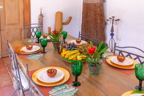 A dining table set with plates, bowls, and green glassware, surrounded by chairs. - Harmony Villa by Fidalsa (Daya Vieja)